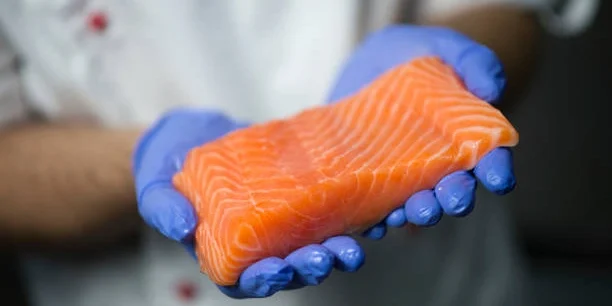 Operario sosteniendo filete de salmón fresco en planta procesadora de alimentos