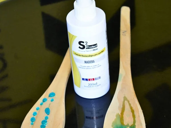 Envase de S2 Madera junto a una prueba comparativa de repelencia al agua sobre madera tratada y sin tratar