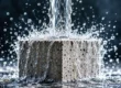 Bloque de hormigón recibiendo un intenso chorro de agua, ilustrando la importancia de proteger las superficies porosas frente a la humedad